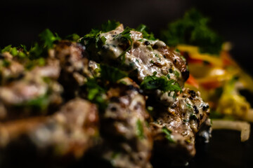 Extreme close up of Chicken Malai Tikka with blurry colorful veggies in the background.