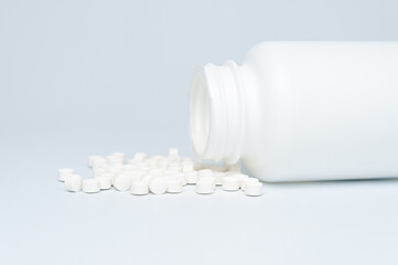 Medical concept - Plastic bottle with scattered white pills. Isolated on white background. Copy space.