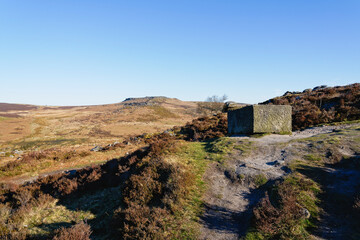 Unfinished stone trough and to distant Higger Tor from Burbage Edge