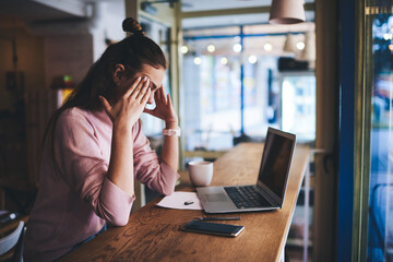 Exhausted student preparing for exam sitting at table in cafe