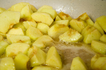 Slices of apples caramelizing in frying pan with sugar