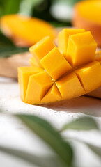Diced fresh mango fruit on a white plate with leaves.