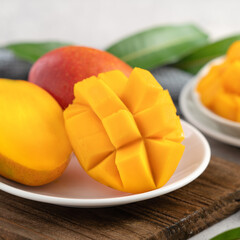 Diced fresh mango fruit on a white plate with leaves.