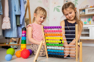 Little children in kindergarten learn to count on abacus, bright wooden toys in the nursery