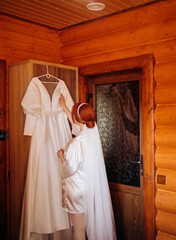 Luxury bride in white robe holding her wedding dress and smiling. cute moment. luxury gown.