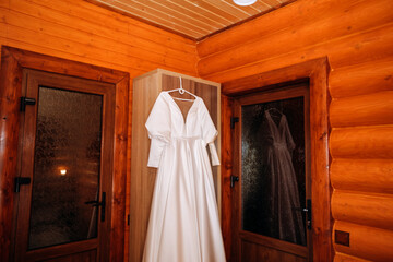 A silk dress hangs on a hanger in a wooden hotel room