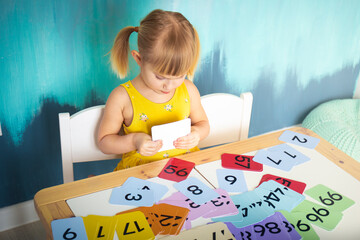 Little caucasian girl studying numbers and math in the classroom, stylish interior for home education, preschool child education, home schooling