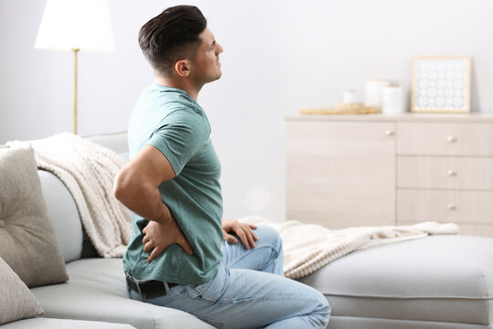 Man suffering from back pain at home. Bad posture problem