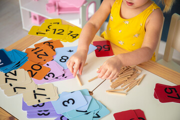 Little caucasian girl studying numbers and math in the classroom, stylish interior for home education, preschool child education, home schooling