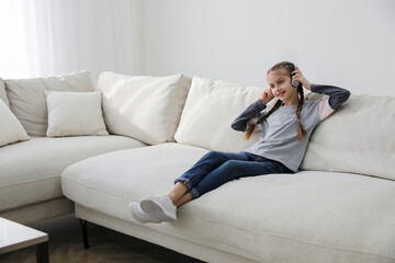 Obraz premium Girl with headphones sitting on comfortable sofa in living room