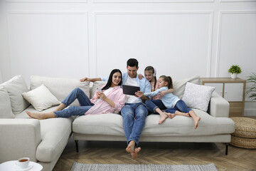 Family with tablet on comfortable sofa in living room