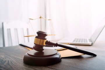 Justice and law concept.Male judge in a courtroom with the gavel, working with, computer and docking keyboard, eyeglasses, on table in morning light