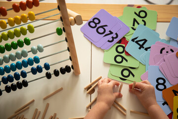 Little caucasian girl studying numbers and math in the classroom, stylish interior for home education, preschool child education, home schooling