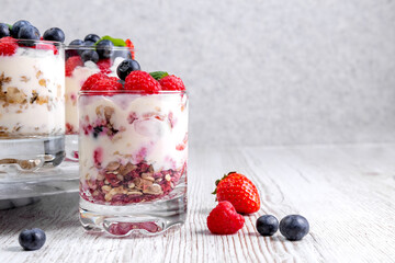 Muesli with yogurt and berries in a glass On a wooden table. Dessert preparation process. Fitness food. Copy space.