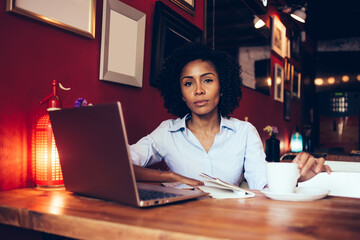 Serious woman with laptop sitting in cafe
