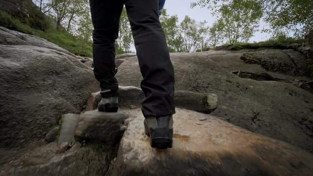 Active backpacker man fast climbing on wet stones mountain walking at rainforest
