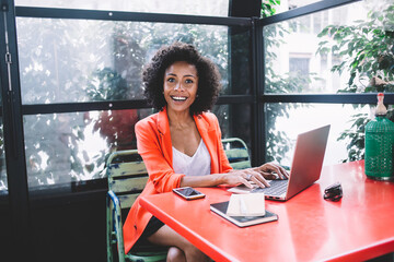 Surprised young black woman typing on laptop in cafe