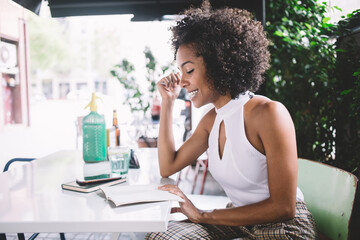 Young woman reading diary and smiling in cafe