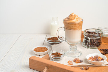 Cold dalgona coffee on a brown tray with ingredients.