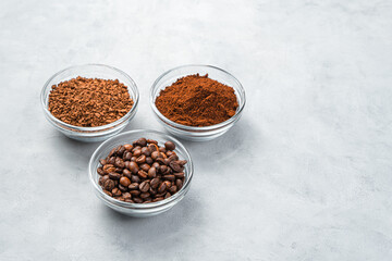 Three cups with different types of coffee on a gray background.