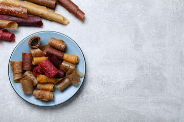 Delicious fruit leather rolls on grey table, flat lay. Space for text