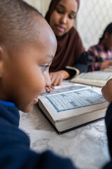 Fototapeta na wymiar Black Muslim mother reading quran with her children