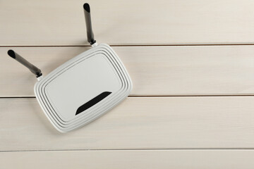 Modern Wi-Fi router on white wooden background, top view. Space for text