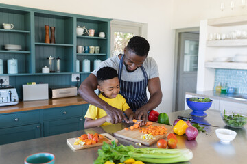 African american father and son in kitchen, cooking together