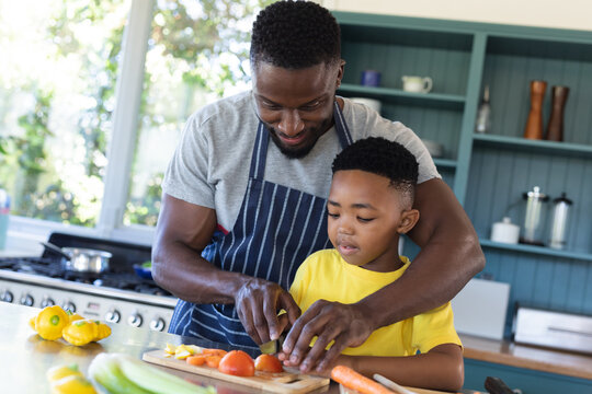 African american father and son in kitchen, cooking together