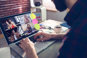 Caucasian businessman sitting at desk using laptop having video call with group of colleagues
