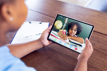 Mixed race businesswoman sitting at desk using tablet having video call