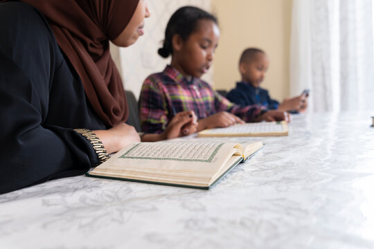 Black Muslim mother reading quran with her children