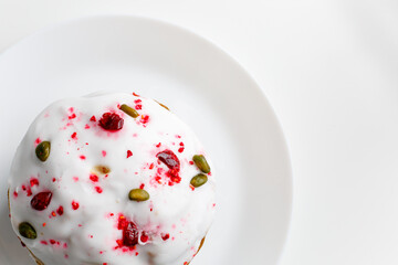 Easter muffin cake with pistachios and cranberry and easter decorations on a white plate. White background. Copy space. 