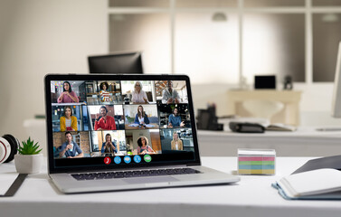 Diverse female and male coworkers having video call on screen of laptop on desk