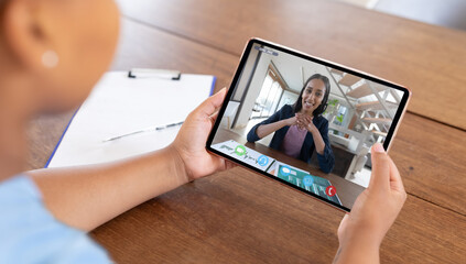 Caucasian woman sitting at desk using tablet having video call with coworker