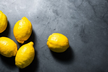 Several ripe lemons on a gray background