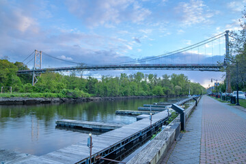 Fototapeta premium Kingston, NY - USA- May 12, 2021: a landscape view of the Wurts Street Bridge or the The Kingston–Port Ewen Suspension Bridge, is a steel suspension bridge spanning Rondout Creek.