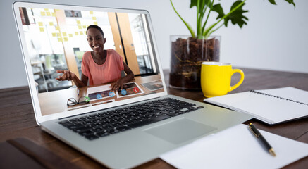 African american woman having video call on screen of laptop on desk