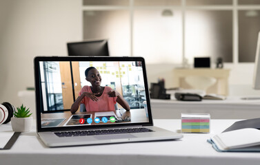 Fototapeta na wymiar African american woman having business video call on screen of laptop on desk