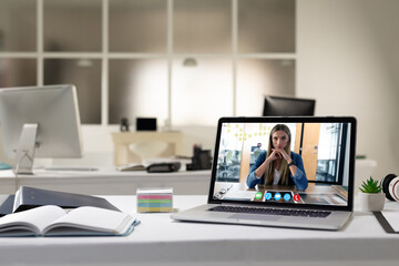 Fototapeta na wymiar Caucasian woman having business video call on screen of laptop on desk