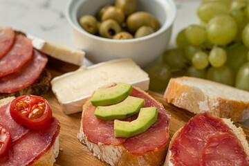 Assortment of sausages and cheese, salami, baguette slices, olives, on white background. Close up