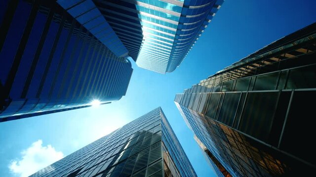 Low angle view of city skyline buildings, blue sky and glass mirrored facades.	