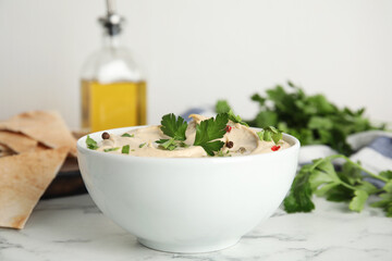 Delicious hummus with parsley and pita chips on white marble table, closeup