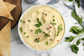 Delicious hummus with parsley and pita chips on white marble table, flat lay
