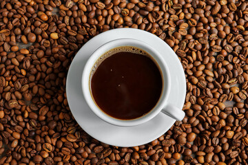 Horizontal banner with a cup of coffee and coffee beans. Top view. Copy space. Espresso or Americano in a cup. Coffee beans background