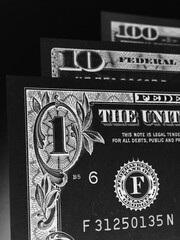 US money banknotes of 1, 10 and 100 dollars. Dark vertical dramatic illustration about the American economy, public finance and taxation. Black and white print that looks like an etching. Macro