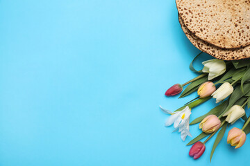 Tasty matzos and fresh tulips on light blue background, flat lay with space for text. Passover...