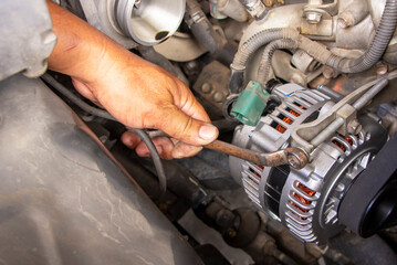 machanic or worker hand-holding wrench repair car alternator in a garage. Repairing and maintenance automobile concept