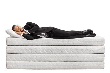 Full length shot of a businessman in a suit and tie sleeping on a pile of mattresses