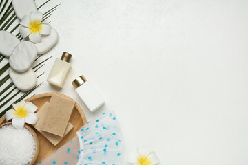 Flat lay composition with shower cap and toiletries on white wooden background. Space for text